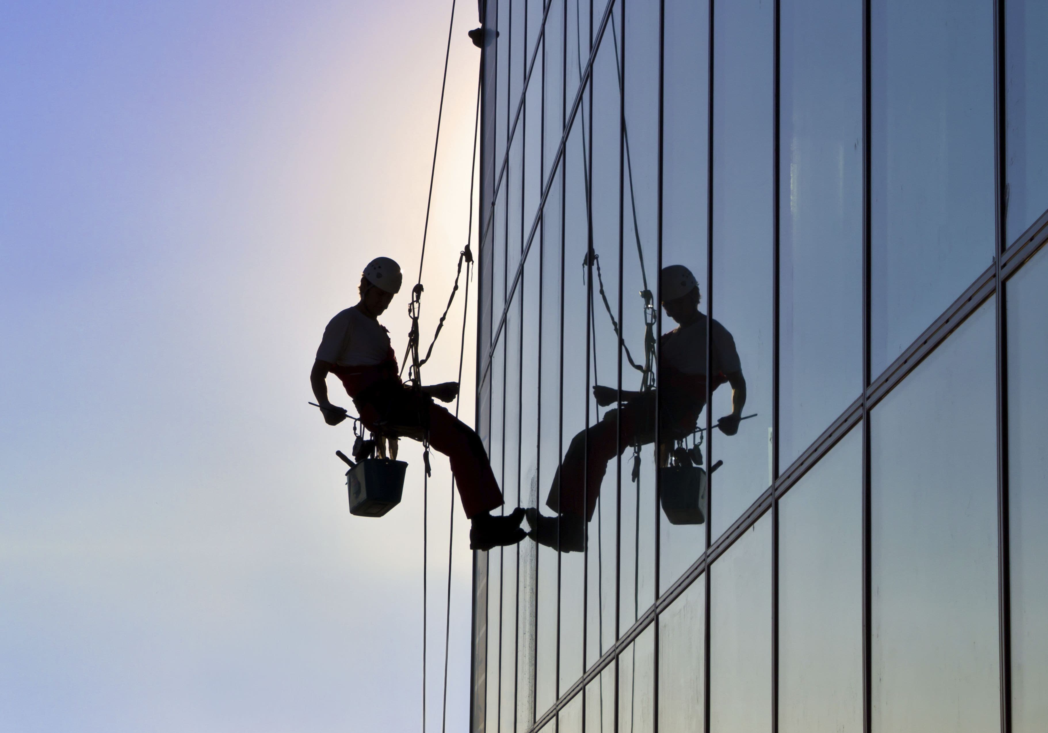 Travail en hauteur sur une façade vitrée au crépuscule